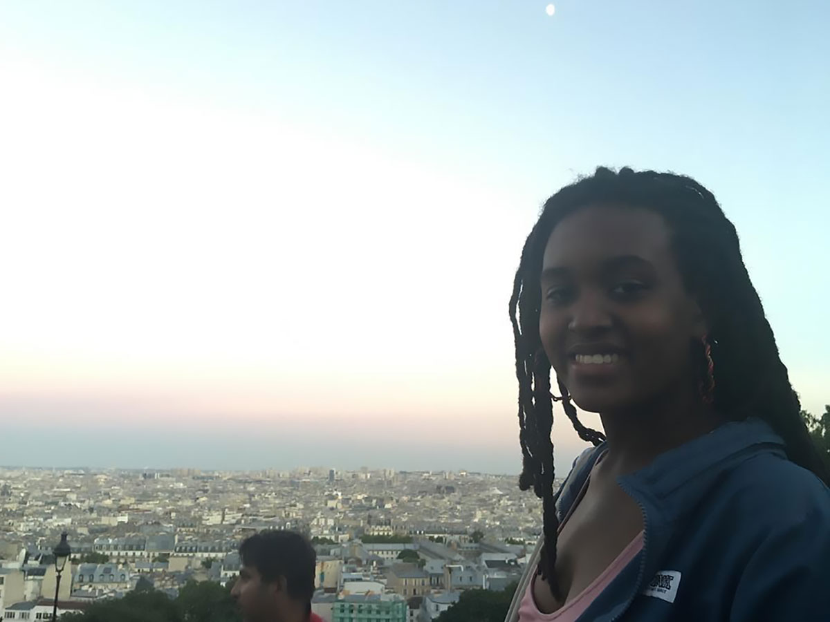 Young woman on a rooftop overlooking the city of Paris.