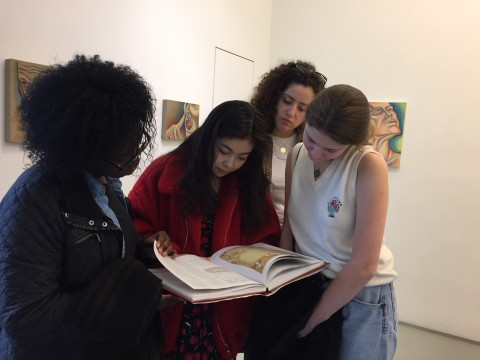 Scholars peruse a catalogue at the Judy Chicago exhibit PowerPlay