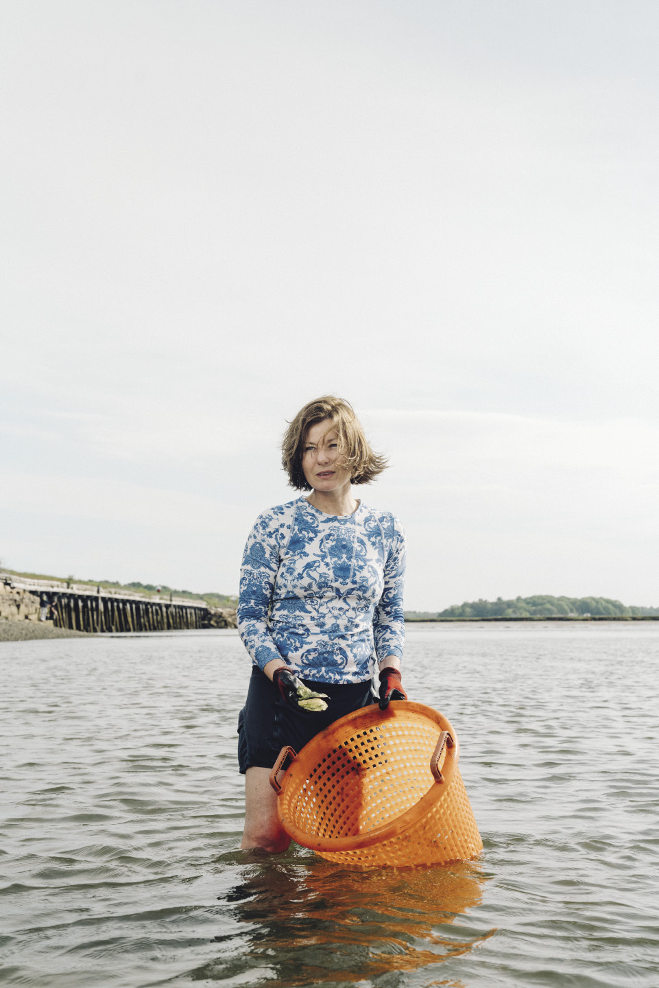 Abigail Carroll ’91 holding a large basket, standing in a body of water