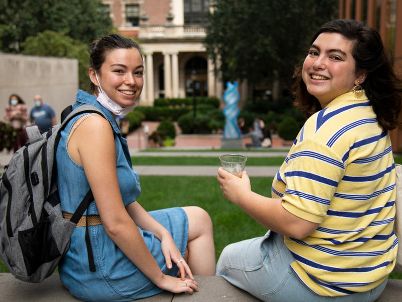 Students sit on campus with "Weecha" statue in the background