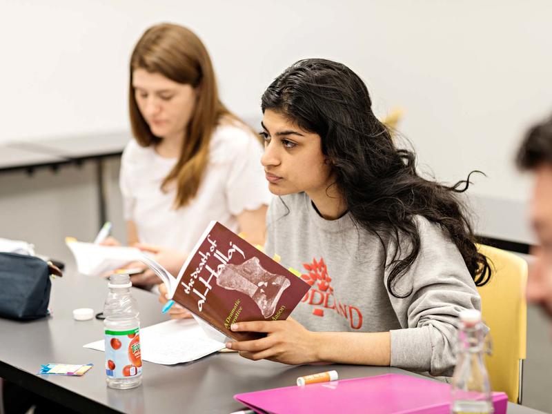 Student in a literature class, holding a text